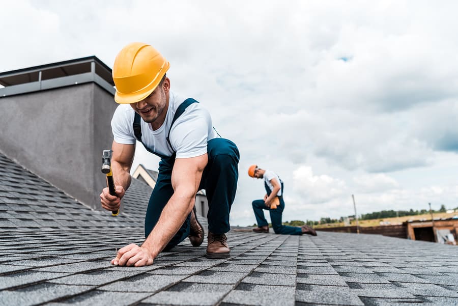 Roofer repairing a shingle roof section
